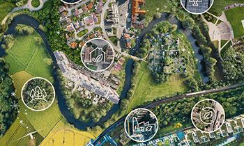 Aerial view of a green landscape blending urban areas with nature, highlighting sustainable solutions like renewable energy, biodiversity, and eco-friendly infrastructure